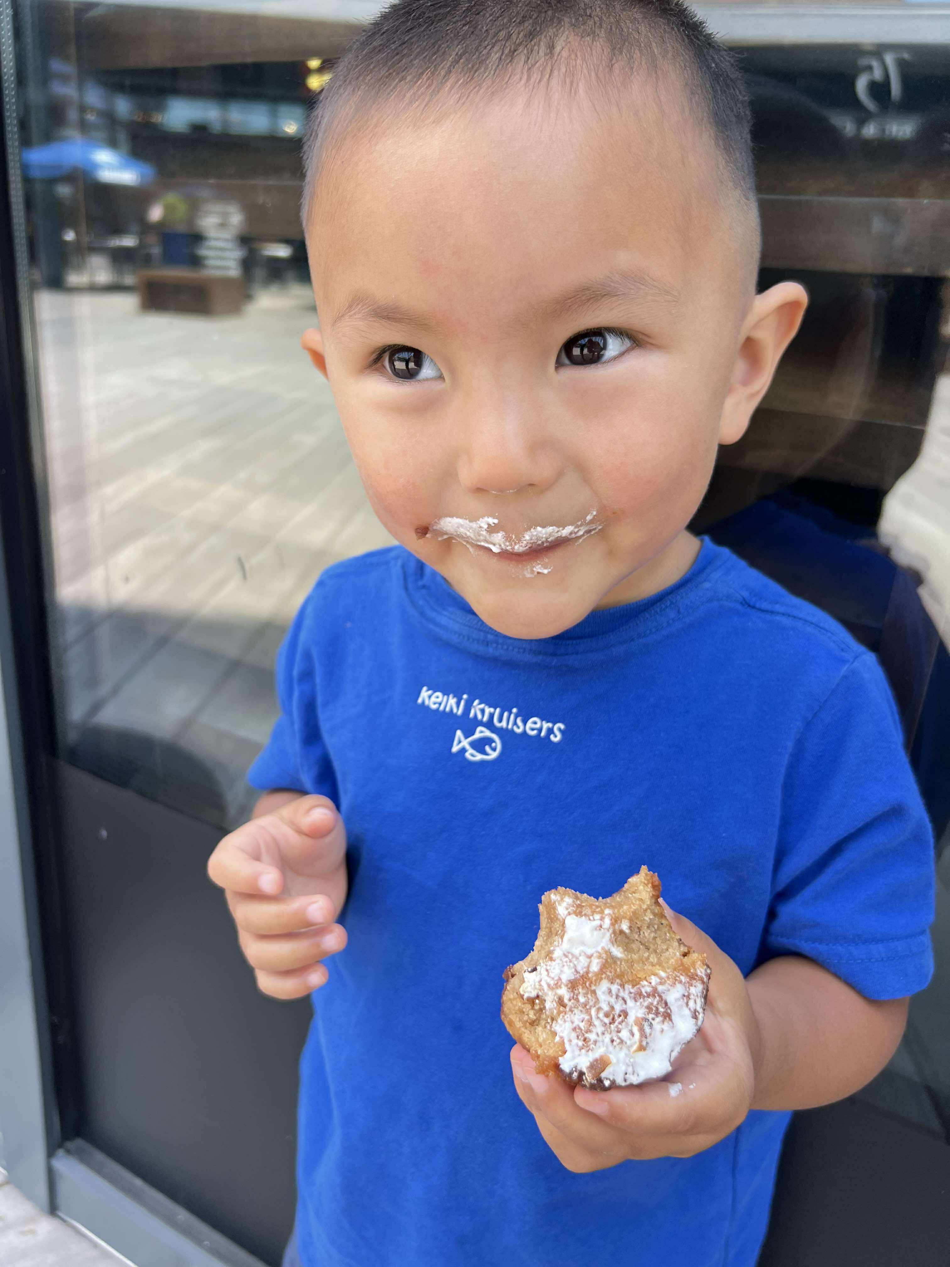 Manu in a Pixlcat Coffee t-shirt enjoying a piece of butter mochi — the perfect gluten-free gift for any occasion